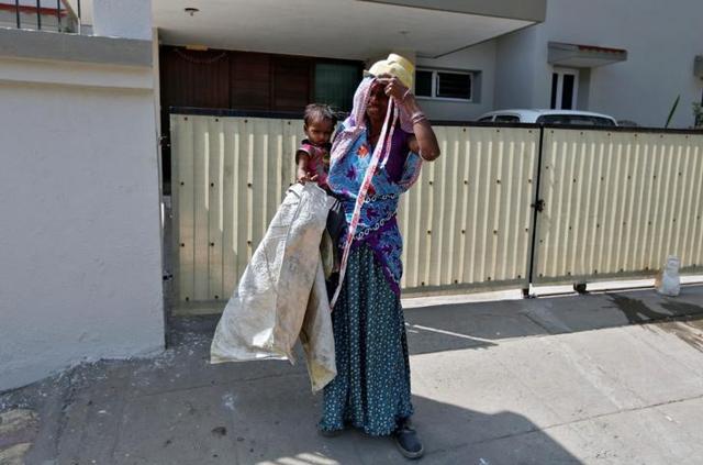 Sarta Kalara holds Shivani as one end of a barrier tape is tied to the 15-month-old’s ankle to prevent her from running away when Kalara works at a construction site nearby in Ahmedabad. (Reuters) Sarta Kalara holds Shivani as one end of a barrier tape is tied to the 15-month-old’s ankle to prevent her from running away when Kalara works at a construction site nearby in Ahmedabad. (Reuters)