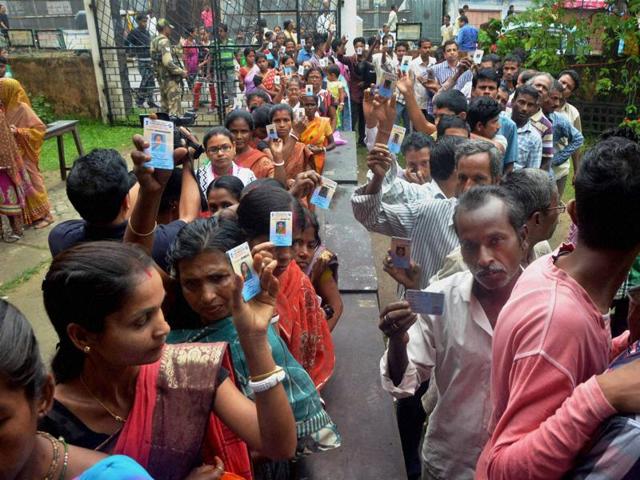 Voters stand in a queue at a polling booth during the first phase of the Assam assembly polls in Silchar. (PTI Photo)