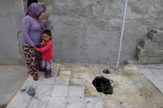 Resident Fattum Gayyaz and her granddaughter stand next to a hole on the roof of her house which was struck by a rocket from Syria, in Kilis. (REUTERS) Resident Fattum Gayyaz and her granddaughter stand next to a hole on the roof of her house which was struck by a rocket from Syria, in Kilis. (REUTERS)