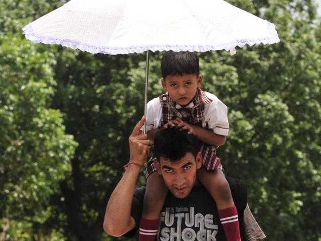 A man and child make do with an umbrella to fight the sun in Mohali on Wednesday. (Keshav Singh/Ht Photo) A man and child make do with an umbrella to fight the sun in Mohali on Wednesday. (Keshav Singh/Ht Photo)