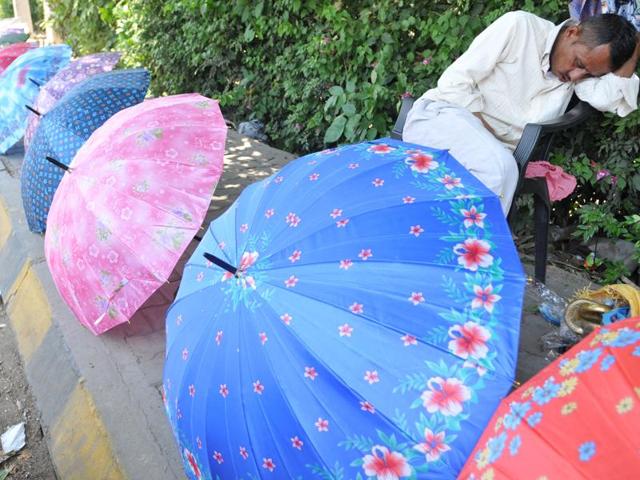 With heat keeping customers away, a roadside umbrella vendor takes a nap in Jalandhar on Wednesday. (Pardeep Pandit/HT Photo) 
