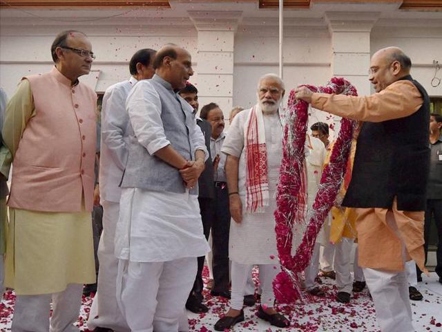 BJP president Amit Shah garlands Prime Minister Narendra Modi as Rajnath Singh and other leaders look on before a meeting at the party office in New Delhi on Thursday.(PTI)