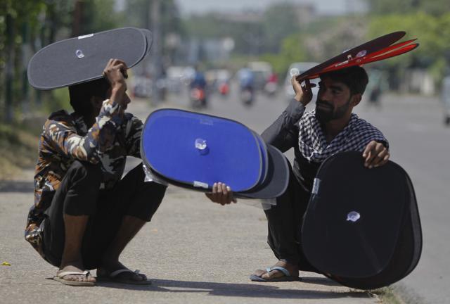 Vendors who sell sunshades for car windows take rest by a roadside on a hot summer afternoon in Jammu. (AP) Vendors who sell sunshades for car windows take rest by a roadside on a hot summer afternoon in Jammu. (AP)