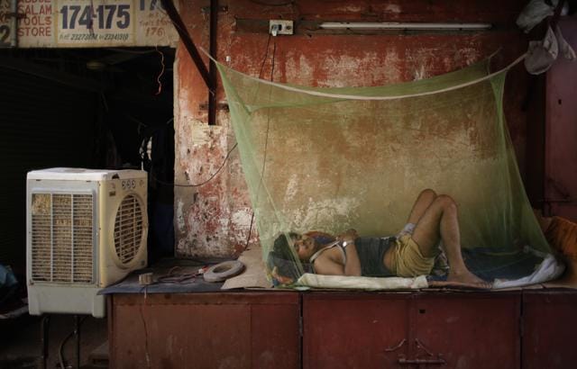 A migrant daily wage worker sleeps next to an air cooler under a mosquito net on a steel box, used to store items of shop at night, in New Delhi. (AP) A migrant daily wage worker sleeps next to an air cooler under a mosquito net on a steel box, used to store items of shop at night, in New Delhi. (AP)