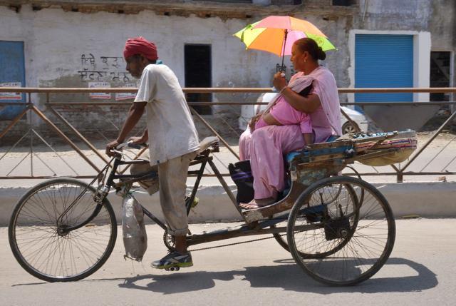 A passenger uses an umbrella to shield herself and her child from the sun on a cycle rickshaw during a hot afternoon in Amritsar. (AFP) A passenger uses an umbrella to shield herself and her child from the sun on a cycle rickshaw during a hot afternoon in Amritsar. (AFP)