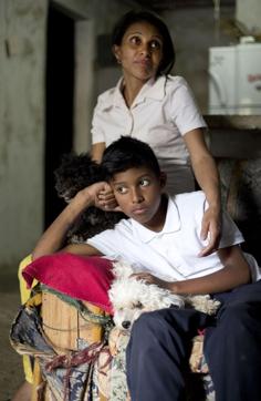 In this May 10, 2016 photo, Roberto Bernal's widow Argelia Gamboa and her 11-year-old son Royber Fuentes sit in their home with the family dogs in a hillside slum in Caracas, Venezuela. (AP) In this May 10, 2016 photo, Roberto Bernal's widow Argelia Gamboa and her 11-year-old son Royber Fuentes sit in their home with the family dogs in a hillside slum in Caracas, Venezuela. (AP)