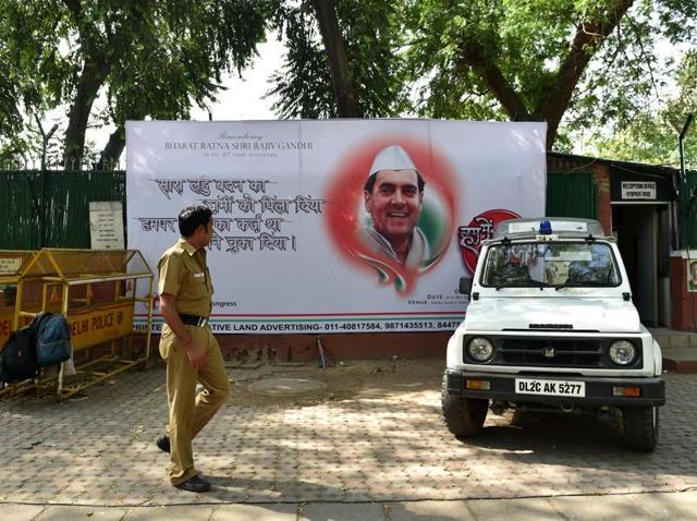 A police officer walks in front of a hoarding bearing the image of former prime minister Rajiv Gandhi outside the All India Congress Committee office in New Delhi.(AFP)