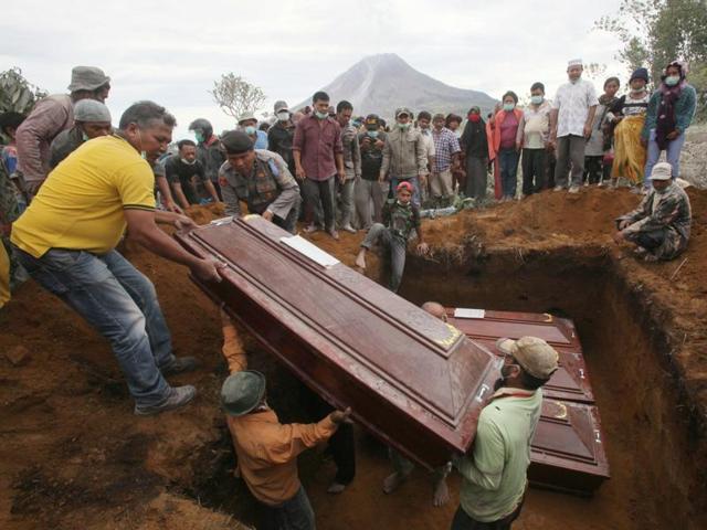 Coffins containing the bodies of the victims in the eruption of Mount Sinabung are lowered into a grave during a funeral in Sukandebi, North Sumatra, Indonesia, Sunday, May 22, 2016. (AP) 