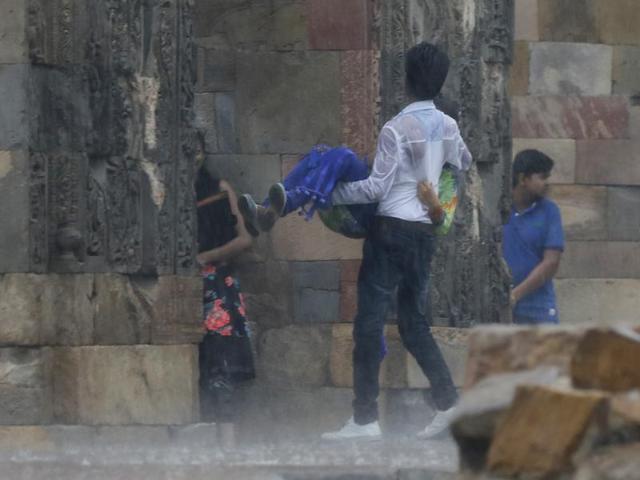 People enjoy the showers at Qutub Minar in New Delhi on Monday. (Sanchit Khanna/ HT Photo)