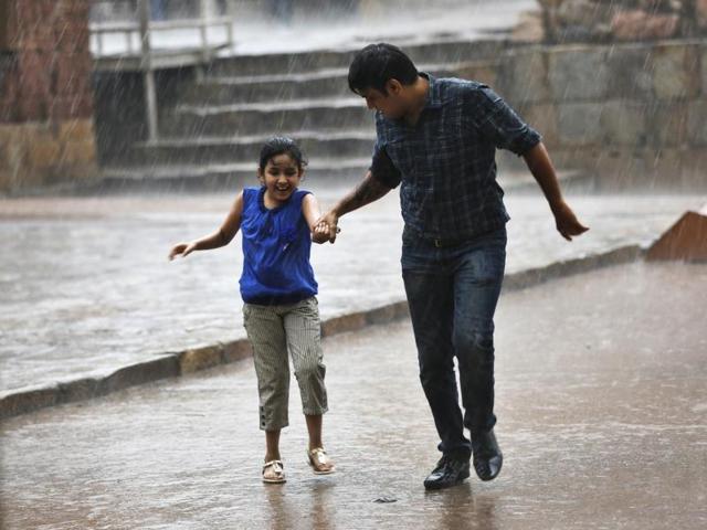 Delhiites enjoy evening rain at Qutub Minar on Monday. The downpour brought much-needed respite to the scorched city.(Sanchit Khanna/ HT Photo)