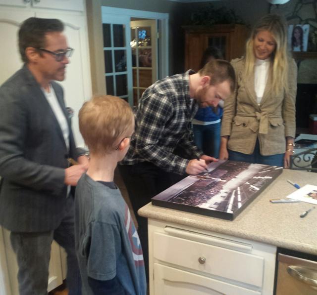 In this photo provided by Amy Wilcox, Captain America Chris Evans signs a photo for Ryan Wilcox, as Iron Man Robert Downey Jr, and Gwyneth Paltrow look on during a visit with Wilcox at his home in El Cajon, Calif. (AP) In this photo provided by Amy Wilcox, Captain America Chris Evans signs a photo for Ryan Wilcox, as Iron Man Robert Downey Jr, and Gwyneth Paltrow look on during a visit with Wilcox at his home in El Cajon, Calif. (AP)