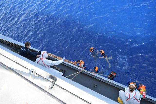 People are helped to board an Italian Navy ship after a boat overturned off the Libyan coast on Wednesday. (AP Photo) People are helped to board an Italian Navy ship after a boat overturned off the Libyan coast on Wednesday. (AP Photo)