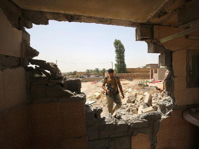 An Iraqi pro-government fighter is seen through a damaged wall as he takes part in an operation in al-Shahabi village, east of Fallujah, to retake the city from Islamic State (IS) group. (AFP) An Iraqi pro-government fighter is seen through a damaged wall as he takes part in an operation in al-Shahabi village, east of Fallujah, to retake the city from Islamic State (IS) group. (AFP)