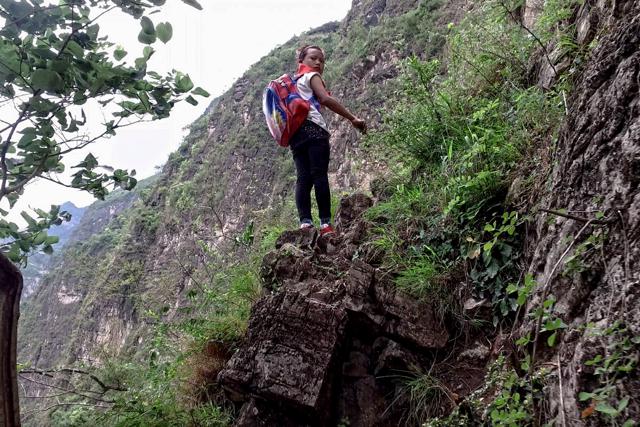 A child with her school backpack takes a rest on a cliff as she and other children return home from school. (AP) A child with her school backpack takes a rest on a cliff as she and other children return home from school. (AP)
