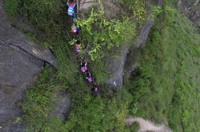 Children carry their school backpacks as they climb a cliff on their way home from school. (AP) Children carry their school backpacks as they climb a cliff on their way home from school. (AP)