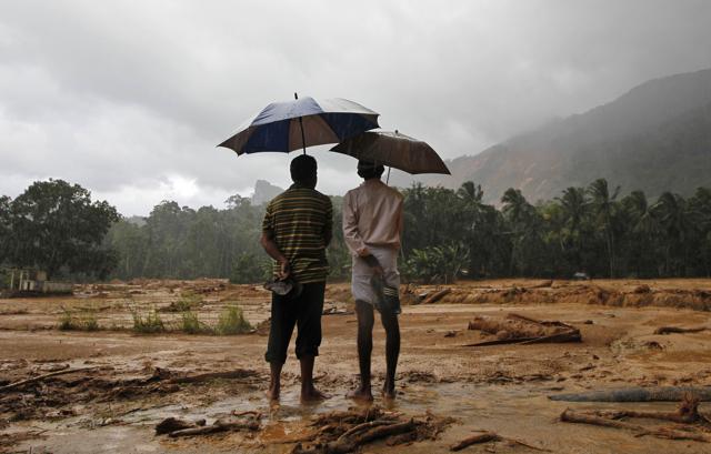 Two survivors hold their sandals as they stand in the mud after a landslide in Elangipitiya village in Aranayaka, Sri Lanka, about 72km northeast of Colombo, on May 18, 2016. (AP)