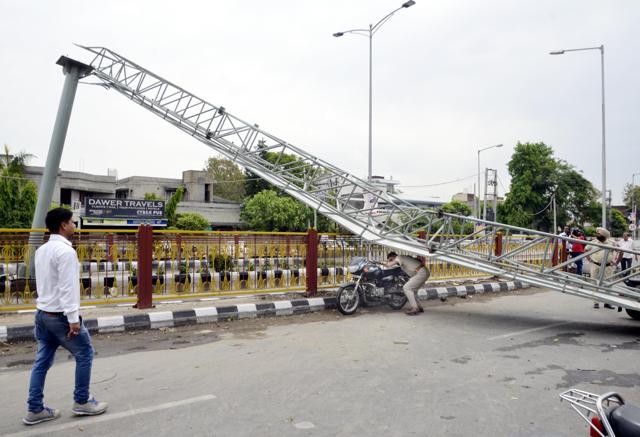 A cop trying to cross a sign board that collapsed at Kitchlew Chowk flyover outside deputy commissioner office in Amritsar on Monday. (Sameer Sehgal/HT Photo)