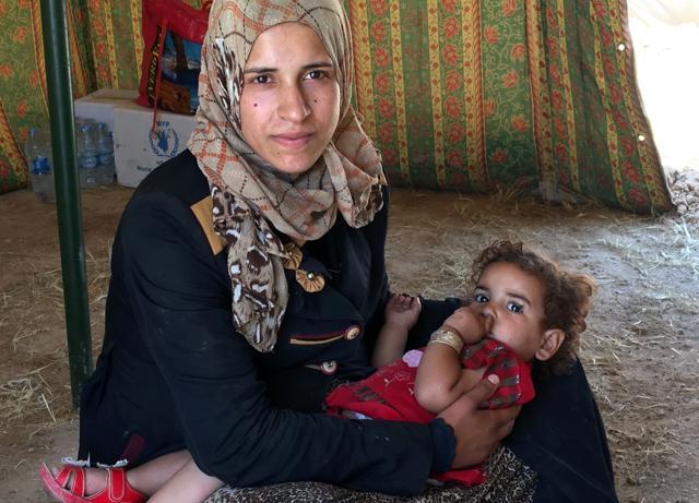 A displaced Iraqi woman cradles her sleeping child inside a tent at a newly-opened camp in the government-held town of Amriyat al-Fallujah. (AFP Photo)