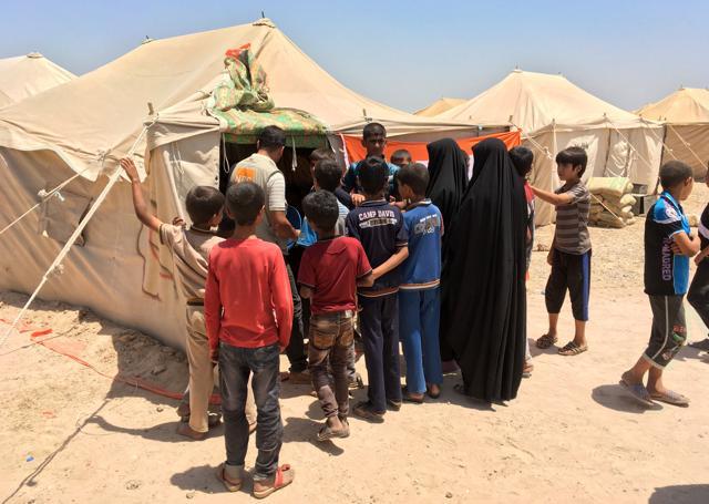 Displaced Iraqis register their families at the entrance of a newly-opened camp in Amriyat al-Fallujah. (AFP Photo)