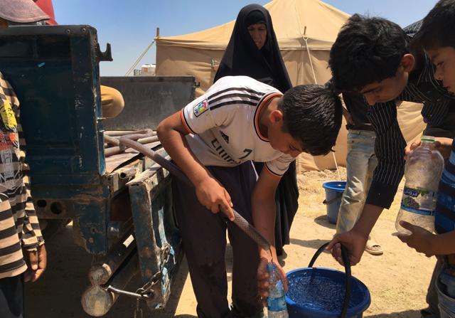 Displaced Iraqi children fill water bottles at a camp in Amriyat al-Fallujah, 50 kilometres southwest of Baghdad, which was set up to shelter people fleeing violence around the city of Fallujah. (AFP Photo)