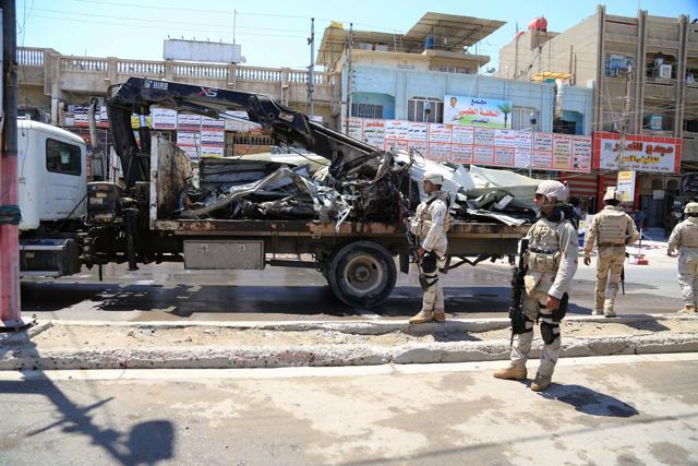 Iraqi security forces stand near the site of a bomb attack in Baghdad northern Shaab district, Iraq. (AP)