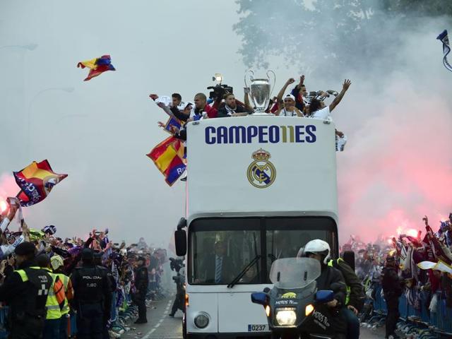 Fans surround the bus as Real Madrid players hold up the trophy celebrating the team's win on Plaza Cibeles in Madrid. (AFP Photo)