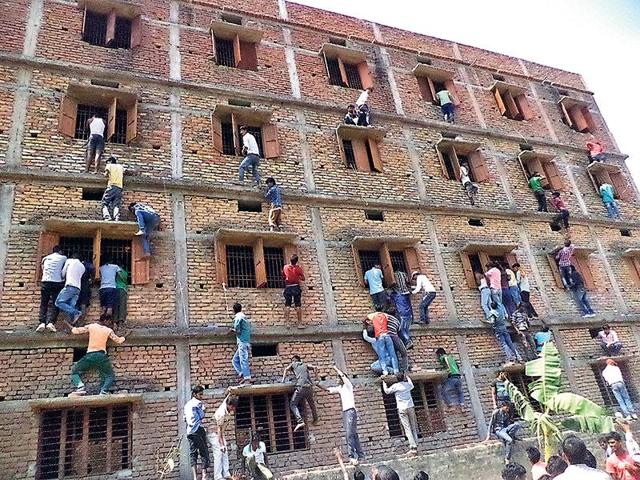 Family members and friends climb walls to make answer chits available to those appearing for their Class 10 exams at a centre in Vaishali, Bihar.(HT file photo)