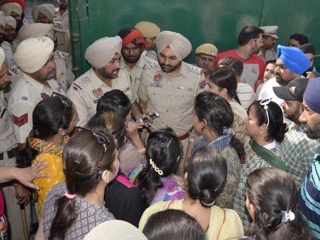 Police officials interacting with protesting parents outside a private school in Amritsar on Wednesday.(HT Photo)