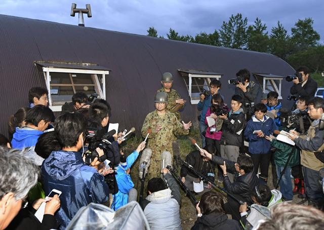 Japan Ground Self-Defense Force Sgt Major Yuichi Kakegawa (centre) speaks to the media outside the hut building, where Yamato Tanooka was found safe. (AP)