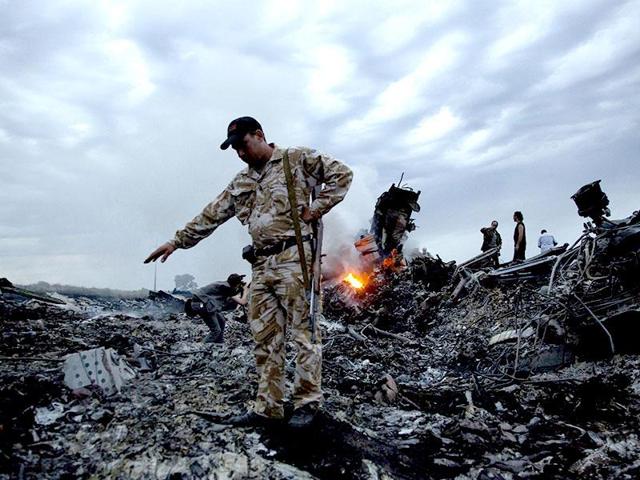 A file photo of people walking on the debris at the crash site of the passenger plane in Ukraine. There has been little definitive progress in determining who brought down Flight MH17. (AP Photo)
