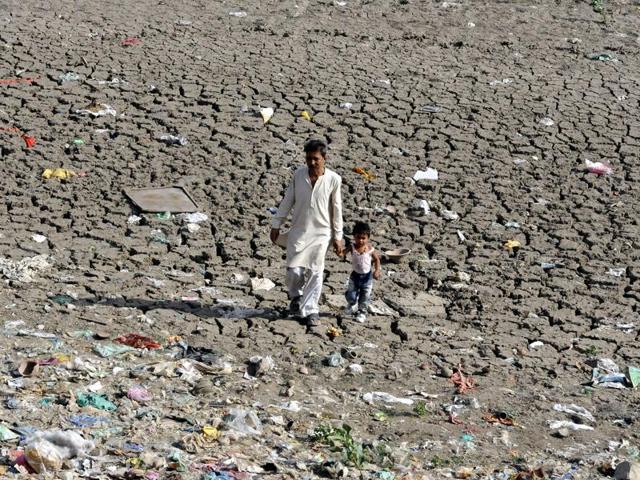 A man and a kid walk through a dried up patch of Pipliyapala lake due to the rise in the temperature. (Arun Mondhe/HT Photo) A man and a kid walk through a dried up patch of Pipliyapala lake due to the rise in the temperature. (Arun Mondhe/HT Photo)