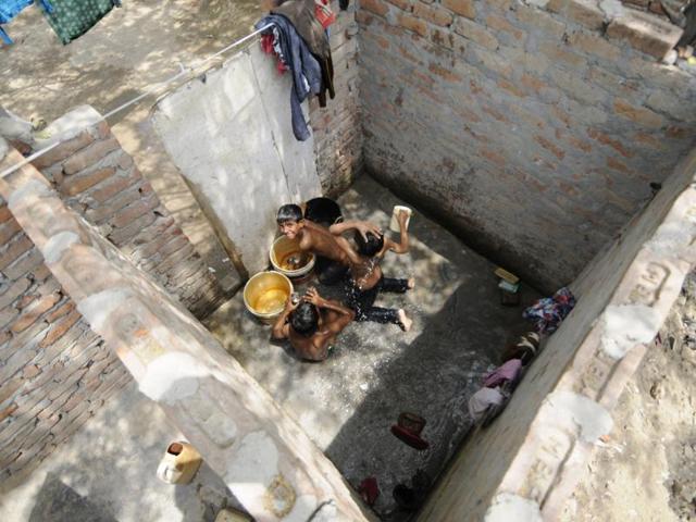 Kids have a bath in an open roofed bathroom. (Burhaan Kinu/HT Photo) 