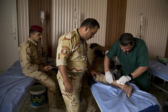 Iraqi Sgt. Hashem Addawi, wounded during fighting against Islamic State militants, is treated for a shrapnel wound after an IS mortar attack at a field aid station at Camp Tariq outside Fallujah in Iraq on Monday. (AP)