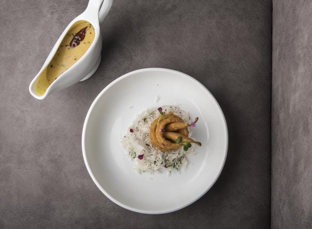 The dishes that work beautifully are undramatic, like the Rajasthani kadhi with pulao, onion rings and batter-fried green chillies, which is served sans smoke, foams, and other forms of nitrogen. (Aalok Soni/ HT Photo)