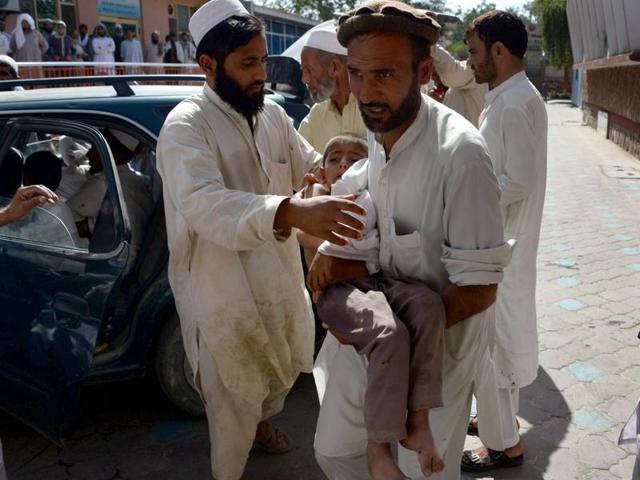 An Afghan volunteer carries a wounded child following an explosion inside a mosque in the Rodat district of Nangarhar province on June 10, 2016.(AFP)