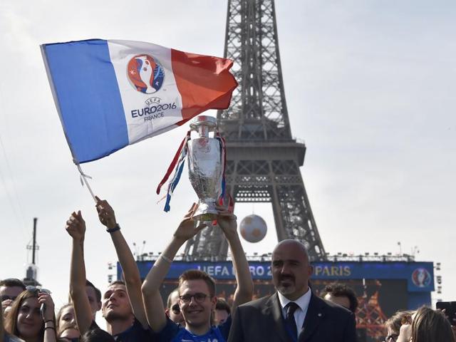 Fans hold up French flags with the Euro 2016 logo as well as replicas of the trophy during the concert. (AFP)