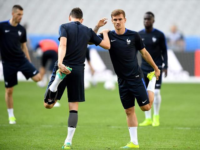 Antoine Griezmann (R) and Laurent Koscielny help each other stretch. (AFP) 