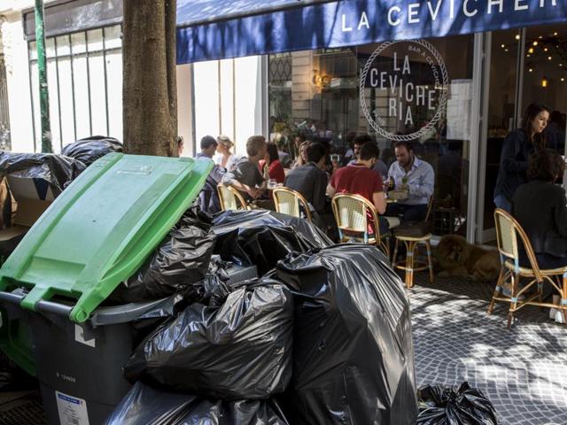 People have lunch past overflowing garbage cans and rubbish bags in Paris, France. (AP Photo) People have lunch past overflowing garbage cans and rubbish bags in Paris, France. (AP Photo)