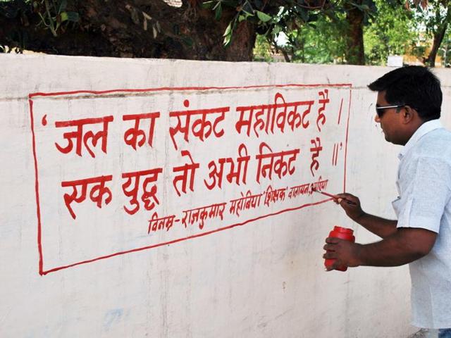 Teacher Rajkumar Mahobia paints a wall of a school in Umaria district. (HT photo) Teacher Rajkumar Mahobia paints a wall of a school in Umaria district. (HT photo)