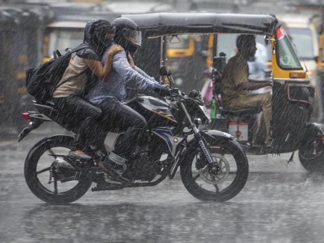 A couple enjoys ride in the rain on western express highway in Mumbai on Saturday. Mumbai experienced its first rain today after a very hot and humid week. (Satish Bate)
