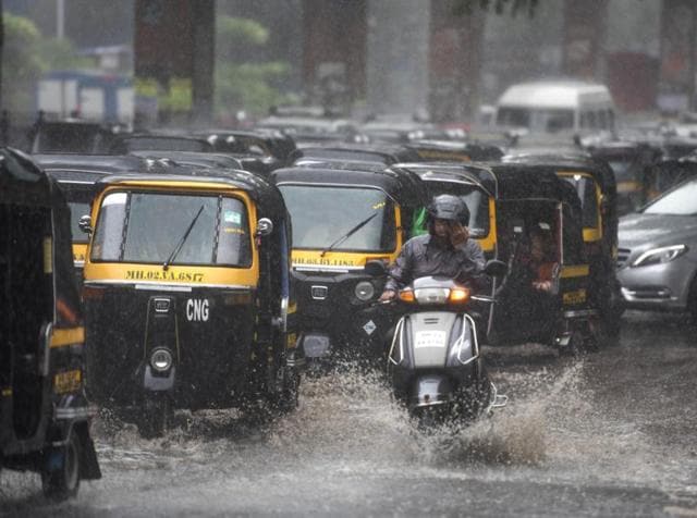 Mumbaikars travel through the logged water after the heavy rain at Santacruz in Mumbai on Saturday. Mumbai experienced its first rain today after a very hot and humid week. (Satish Bate)