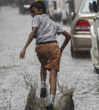A boy enjoys flooded street during the rain at Sion in Mumbai on Saturday. Mumbai experienced its first rain today after a very hot and humid week. (Kunal Patil)