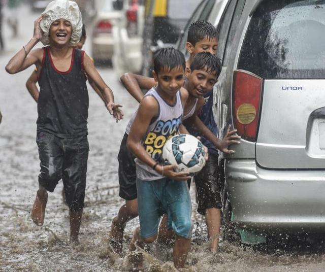 Children enjoy football game in the water logged street during the rain at Sion in Mumbai on Saturday. Mumbai experienced its first rain today after a very hot and humid week. (Kunal Patil)