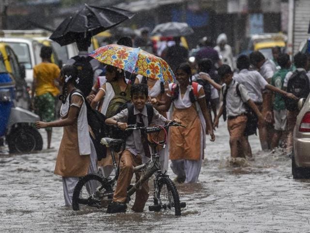 School kids wade through the flooded street during the rain at Sion in Mumbai on Saturday. Mumbai experienced its first rain today after a very hot and humid week. (Kunal Patil)