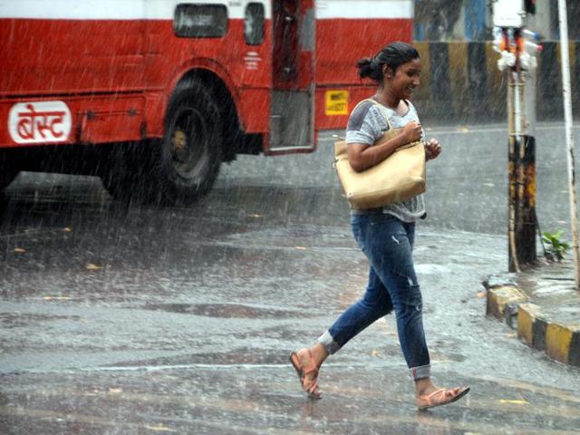 A lady run for the cover as she cought unaware in sudden shower at Mahim in Mumbai on Saturday. Mumbai experienced its first rain today after a very hot and humid week. (Sandeep Mahankal)