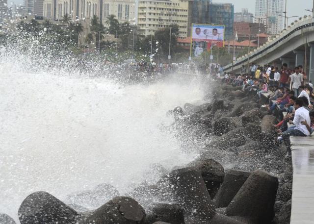 People enjoying high tide at marine drive in Mumbai on Saturday. Mumbai experienced its first rain today after a very hot and humid week. (Prashant Waydande)