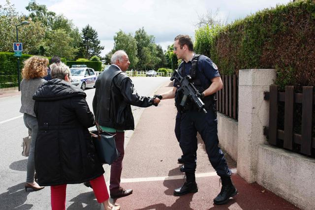 A man shakes hands with a French policeman to thank him as he returns to his house in a street of Magnanville where a man claiming allegiance to the Islamic State group killed a French policeman and his partner on the night of June 13. (AFP)