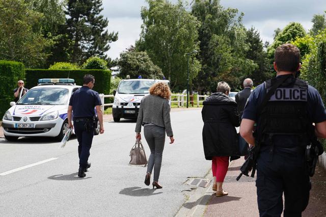 French policemen escort neighbours returning to their house in the street of Magnanville where a man claiming allegiance to the Islamic State group killed a French policeman and his partner on the night of June 13. (AFP)