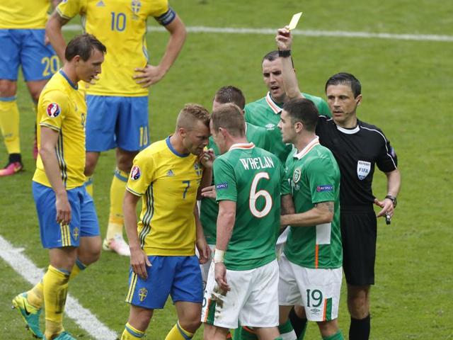 Referee Milorad Mazic, right, shows the yellow card to Republic of Ireland's Glenn Whelan, centre, as he argues with Sweden's Sebastian Larsson, second left. (AP)