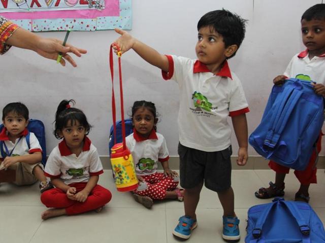 New place, new rules: A child seems unhappy while giving away his water bottle to the teacher. (PRAFUL GANGURDE) 